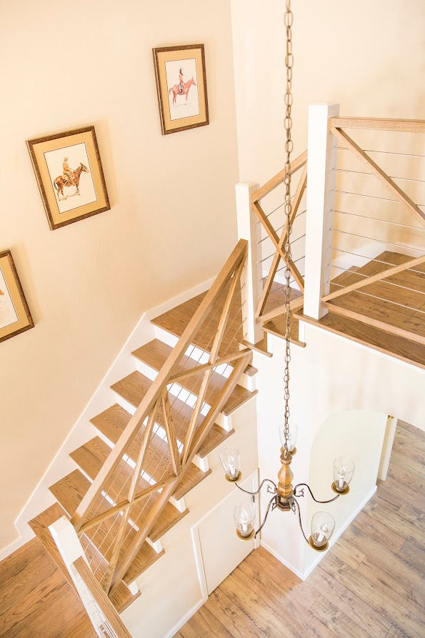 Wooden staircase with railing and chandelier in a home interior.